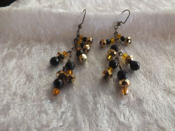 Dangles of black and gold and black and orange hang from 3 1/4" of black chain.